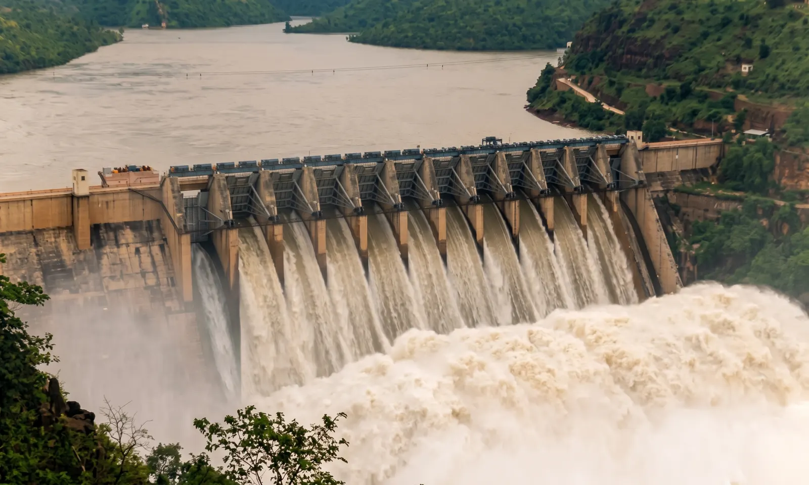 Water rushing through the open spillway gates of a river dam